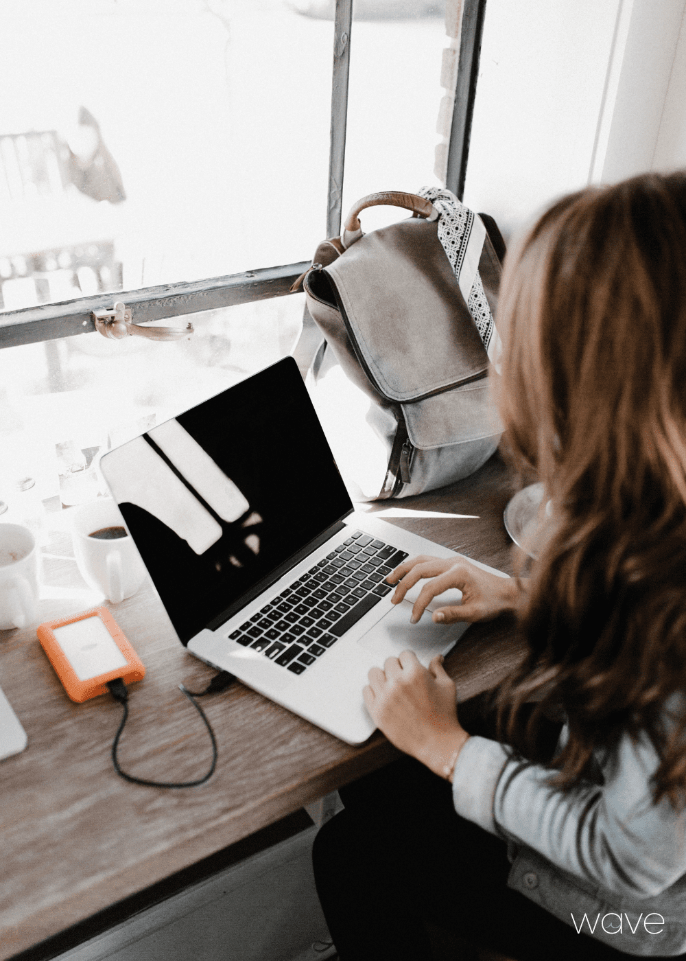 A woman is working in a coffee shop on her computer.